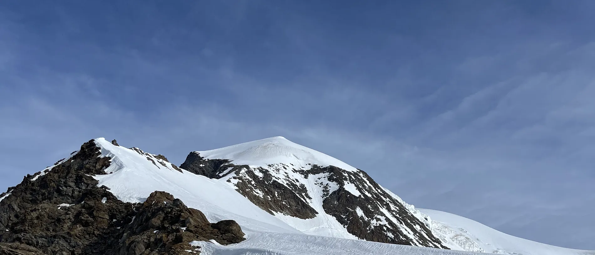 Verschneiter Gipfelaufbau mit steilem Firnhang unter blauem Himmel