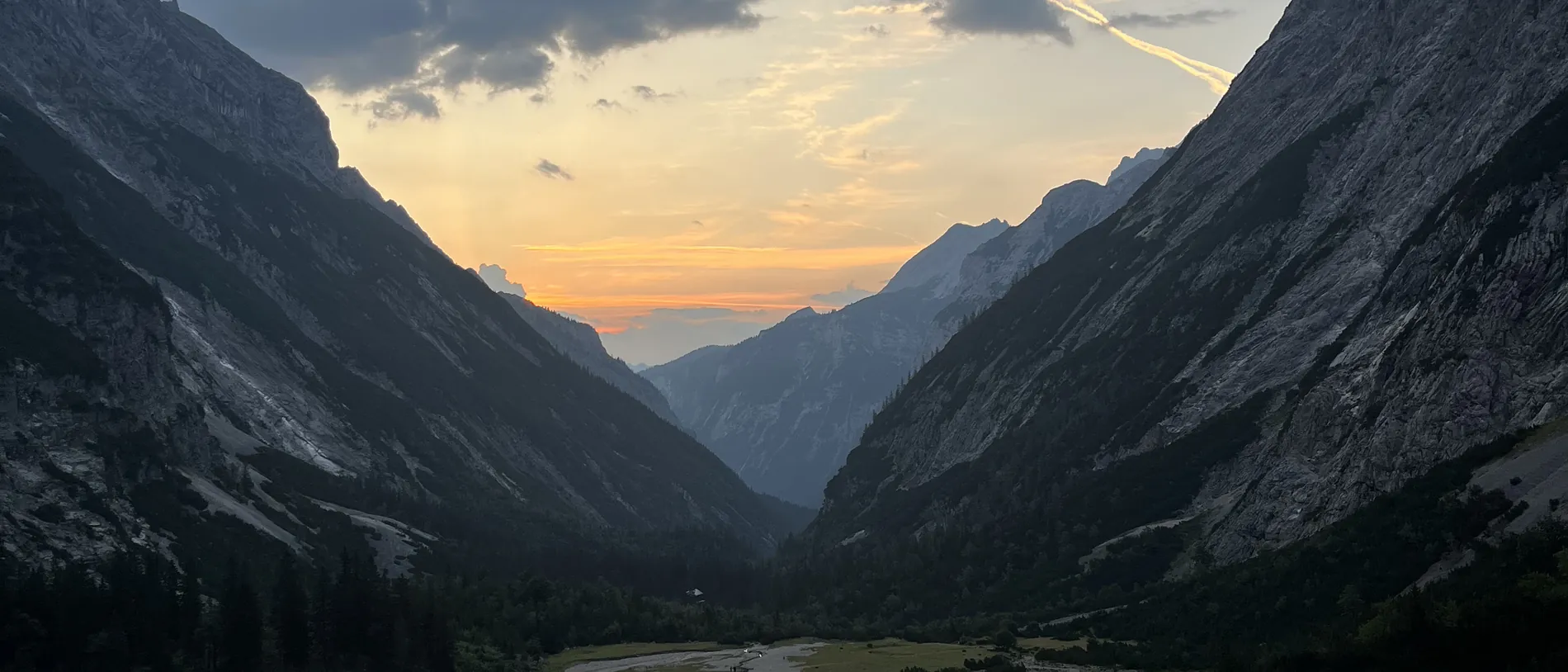Abendstimmung über einem Alpental zwischen steilen Bergflanken